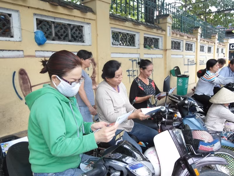 Các bà mẹ đang “giết thời gian” bằng những tờ báo trong lúc chờ con thi môn Tiếng Anh tại trường Marie Curie.