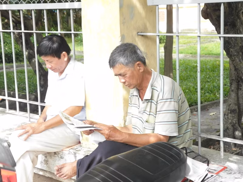 Cách vị phụ huynh “sành điệu” không xa là một phụ huynh khác đang chăm chú với tờ báo.