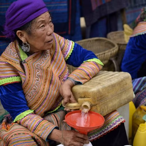 Một người phụ nữ dân tộc thiểu số khác đang bán rượu trắng ở chợ Bắc Hà. Một người phụ nữ dân tộc thiểu số khác đang bán rượu trắng ở chợ Bắc Hà.