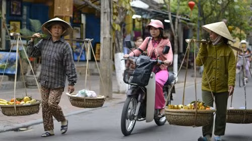 Người gánh hàng, người chạy xe máy trên đường phố Hội An, đoạn gần chiếc cầu Nhật Bản. Người gánh hàng, người chạy xe máy trên đường phố Hội An, đoạn gần chiếc cầu Nhật Bản.