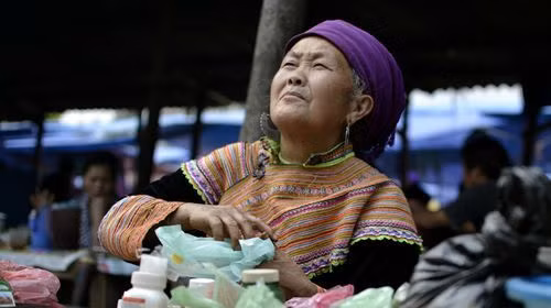 Người phụ nữ H'mong với chiếc áo thổ cẩm sặc sỡ này đang bán thuốc thảo dược ở chợ Bắc Hà, miền Bắc Việt Nam, gần biên giới với Trung Quốc. Người phụ nữ H'mong với chiếc áo thổ cẩm sặc sỡ này đang bán thuốc thảo dược ở chợ Bắc Hà, miền Bắc Việt Nam, gần biên giới với Trung Quốc.