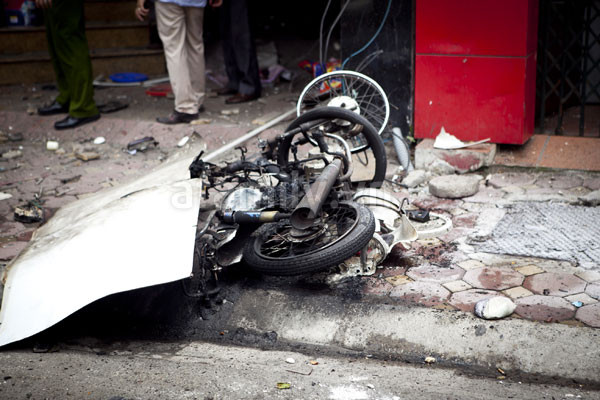 Hiện trường sau vụ nổ: các biển cửa hàng rời ra, chiếc xe máy bị cháy rụi, những mảnh thủy tinh vương vãi khắp nơi... (Ảnh: Afamily.vn)