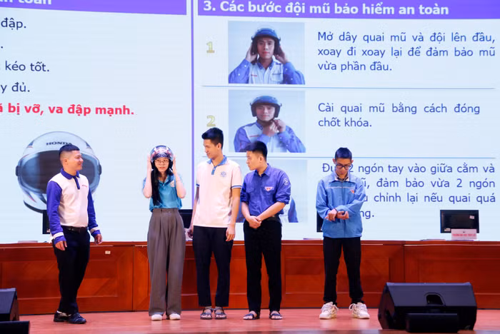 Sinh viên được hướng dẫn các bước đội mũ bảo hiểm đúng cách.