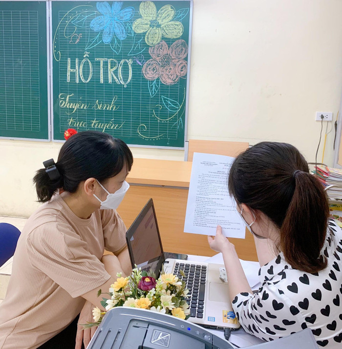 Giáo viên tận tình hướng dẫn phụ huynh. Trước đó, Sở Giáo dục và Đào tạo Hà Nội đã lưu ý: Tuyệt đối không được lấy lại mật khẩu trên hệ thống cơ sở dữ liệu ngành đã được cấp cho học sinh. Trường hợp đã thay đổi mật khẩu, giáo viên chủ nhiệm phải hỗ trợ và cung cấp cho phụ huynh đảm bảo việc đăng ký tuyển sinh trực tuyến bảo mật và thuận lợi. (Ảnh: Trường Tiểu học Ba Đình).