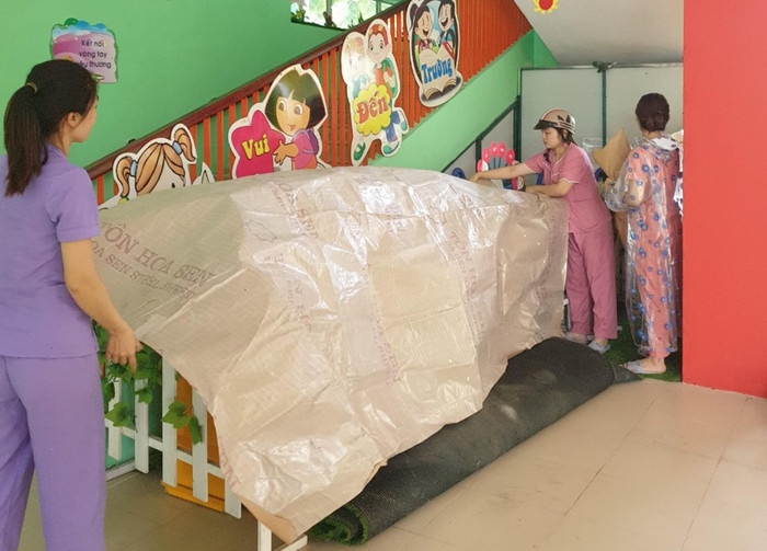 Các giáo viên che chắn đồ dùng học tập cho trẻ.