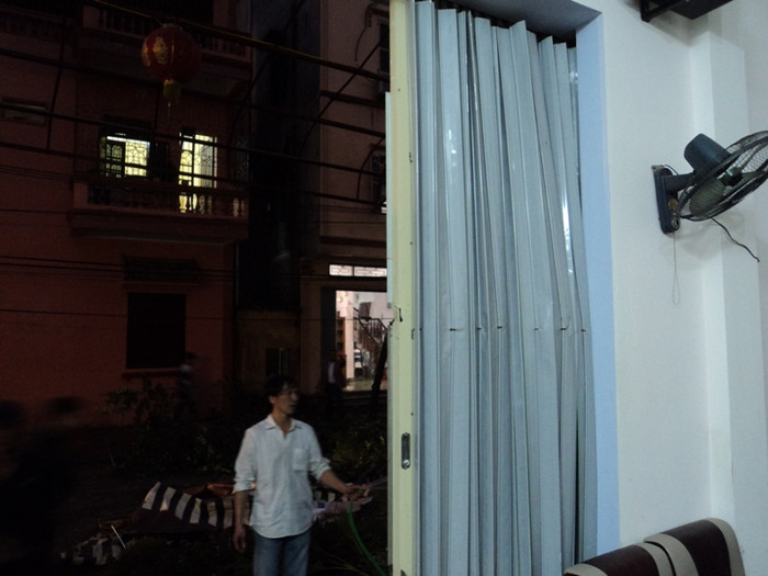 Một người dân đang rửa tường nhà mình và cả tấm cửa thép bị biến dạng do ảnh hưởng bởi vụ nổ kinh hoàng Một người dân đang rửa tường nhà mình và cả tấm cửa thép bị biến dạng do ảnh hưởng bởi vụ nổ kinh hoàng