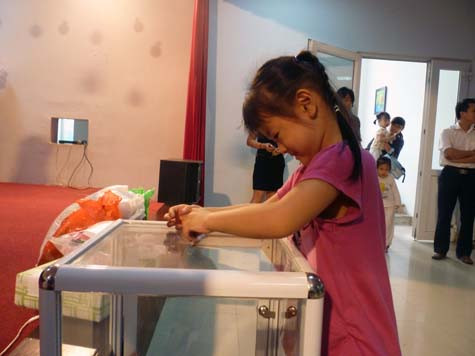 Các bé trường mầm non Vimeco vui mừng cẩn thận nhét tiền vào thùng ủng hộ học sinh nghèo miền núi. (Ảnh Thu Hòe)