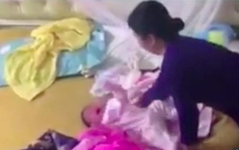 Bà Hoàn đang đánh bé mới hơn 1 tháng tuổi (ảnh từ clip - nguồn vov.vn). Bà Hoàn đang đánh bé mới hơn 1 tháng tuổi (ảnh từ clip - nguồn vov.vn).