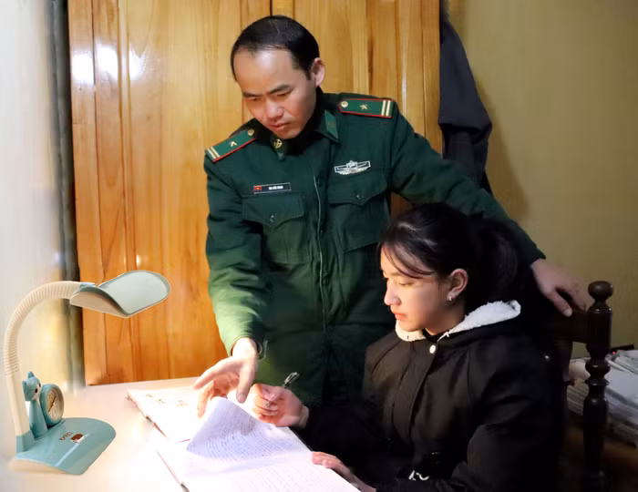 Thiếu tá Ma Đức Minh - Chính trị viên Đồn Biên phòng Phó Bảng hướng dẫn cô con gái út Vàng Thị Chở làm bài tập. Ảnh: Vương Anh.