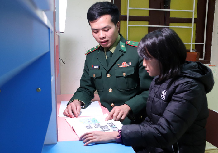 Trung úy Vù Xuân Hùng trực tiếp kèm bài cho con nuôi Thò Thị Súa. Ảnh: Mộc Quế Anh.