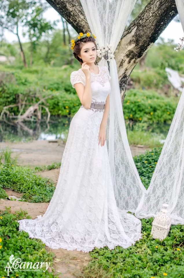 Hot girl Lilly Luta là một mỹ nhân đang được rất nhiều nhiếp ảnh gia săn đón. Với gương mặt dễ thương như một thiên thần và một thân hình nhỏ nhắn rất hợp với những chiếc váy kiểu ren dáng dài. Thiết kế không quá cầu kỳ, chiếc đai thắt làm toát lên vòng eo gợi cảm của Lilly. Và thay vì khăn voan là vòng hoa đội đầu nhẹ nhàng nhưng tuyệt xinh.