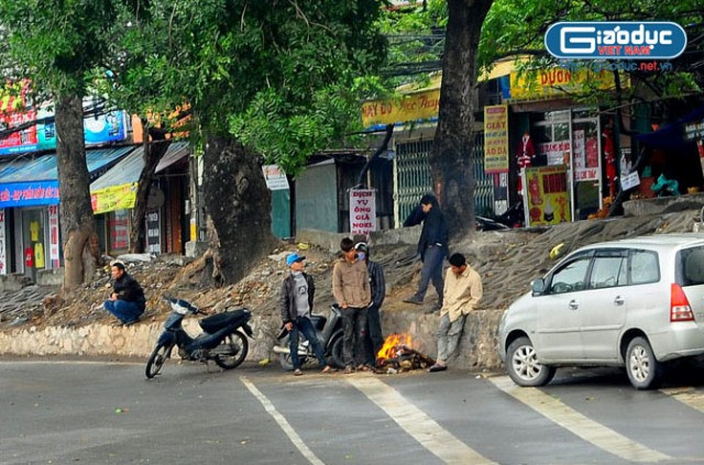 Tại cuối đường Hoàng Quốc Việt, một nhóm người lao động đang đốt lửa sưởi ấm khi chưa có việc Tại cuối đường Hoàng Quốc Việt, một nhóm người lao động đang đốt lửa sưởi ấm khi chưa có việc