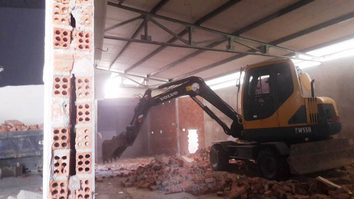 Một chiếc máy múc khác đang phá dở khu chứa hàng nằm gần sát đường. Một chiếc máy múc khác đang phá dở khu chứa hàng nằm gần sát đường.