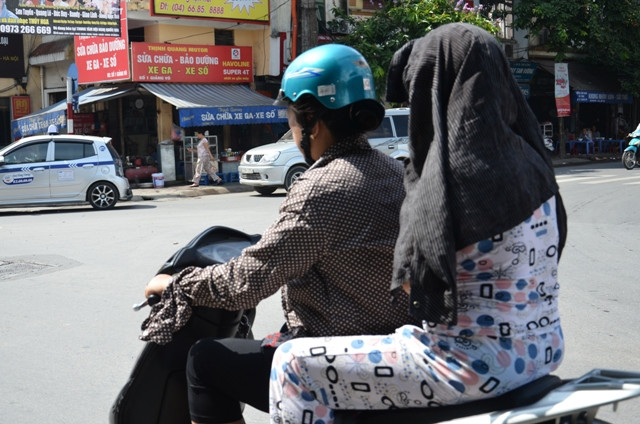 Thay vì đội mũ bảo hiểm thì người phụ nữ này dùng áo đội lên đầu để chống nắng.