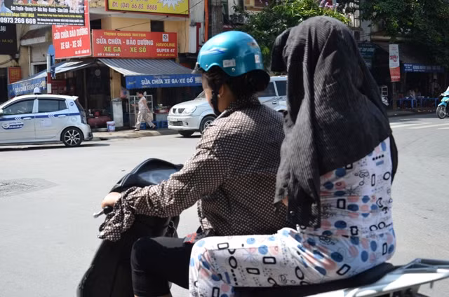 Thay vì đội mũ bảo hiểm thì người phụ nữ này dùng áo đội lên đầu để chống nắng.