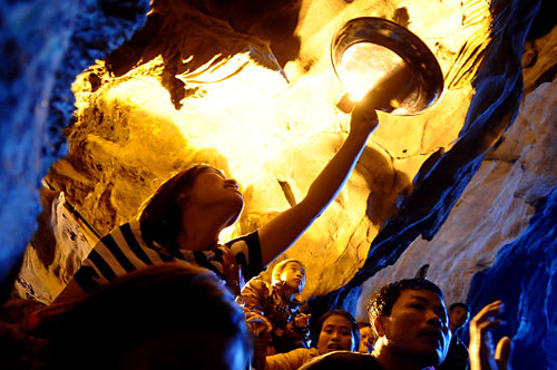 Trong động có những khối thạch nhũ liên tục nhỏ nước xuống nên ai cũng muốn hứng lấy giọt nước cầu may. Một cô gái dùng cả khay đựng đồ lễ trèo lên cao chờ hứng nước. Trong động có những khối thạch nhũ liên tục nhỏ nước xuống nên ai cũng muốn hứng lấy giọt nước cầu may. Một cô gái dùng cả khay đựng đồ lễ trèo lên cao chờ hứng nước.