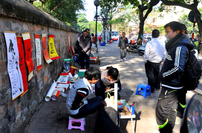 Phía ngoài vỉa hè Văn Miếu vẫn còn đó những ông đồ không có diện tích hoạt động trong “Phố ông Đồ” vẫn vừa bán chữ vừa chạy. Phía ngoài vỉa hè Văn Miếu vẫn còn đó những ông đồ không có diện tích hoạt động trong “Phố ông Đồ” vẫn vừa bán chữ vừa chạy.