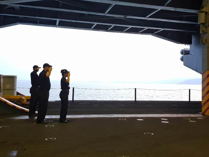 Ba thủy thủ trên tàu sân bay thực hiện nghi lễ chào khách kiểu nhà binh.