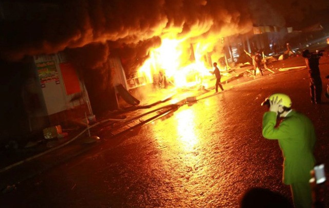 Người dân thẫn thờ nhìn ngọn lửa nuốt trọn các gian hàng. (Ảnh: Thanh Phương/Vietnam+)