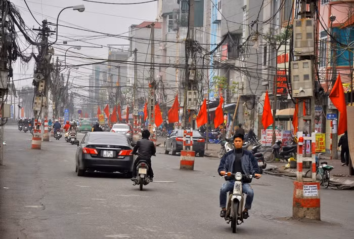 Phần mặt đường đã bằng phẳng nhưng các phương tiện đi vào đường Tân Mai như lạc vào một mê cung cột điện mọc tua tủa giữa đường.