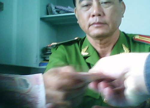 Trung tá Văn nhận tiền bảo kê xe của anh H. - Ảnh: Hoài Nam