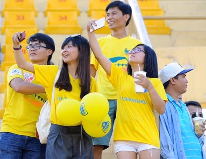 CĐV nữ nhí nhảnh selfie trên khán đài trước trận đấu.