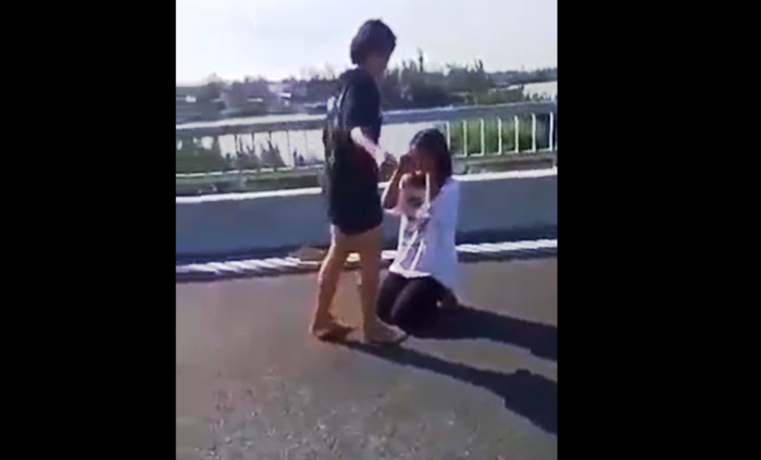 Nữ sinh áo trắng bị bạn đánh nhập viện ngay trên cầu. Ảnh cắt từ clip Nữ sinh áo trắng bị bạn đánh nhập viện ngay trên cầu. Ảnh cắt từ clip