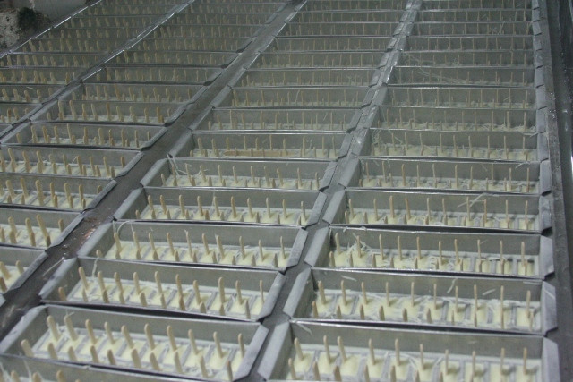 Những que kem sau khi cho vào khuôn được xếp trong các khay giữ nhiệt độ thấp dưới 0 độ C để làm đông lạnh Những que kem sau khi cho vào khuôn được xếp trong các khay giữ nhiệt độ thấp dưới 0 độ C để làm đông lạnh