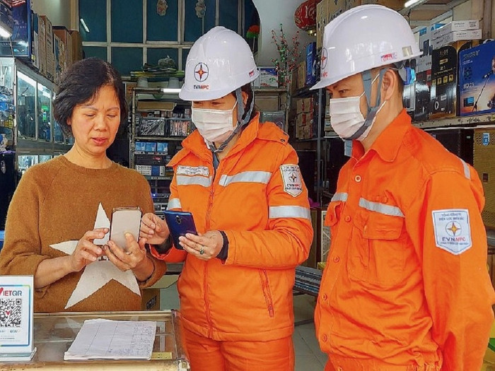 Nhân viên của EVNNPC hướng dẫn khách hàng thanh toán hóa đơn điện qua điện thoại di động