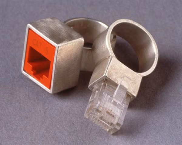 4. Nhẫn đôi Ethernet rings Nếu như chiếc nhẫn mang phong cách USB không đủ gây ấn tượng thì cặp nhẫn đôi hình cổng cáp kết nối Internet chắc chắn sẽ thuyết phục được những người ham mê công nghệ. Cặp nhẫn này gồm một chiếc là cáp và một chiếc là cổng cáp được gắn trên mặt, chất liệu nhẫn được làm từ bạc và hai chiếc có thể cài vào nhau tượng trưng cho mối tình bên lâu giữa cô dâu và chú rể. Cặp nhẫn cưới này có giá khoảng 340 đôla/cặp, giá khá rẻ so với tính “độc” của nó.