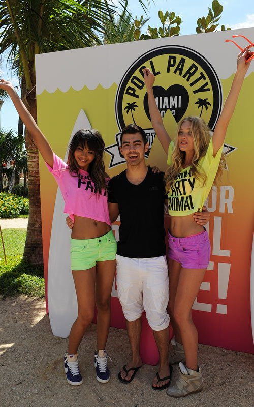 Joe Jonas quàng tay qua ôm eo hai siêu mẫu với nụ cười trên môi.