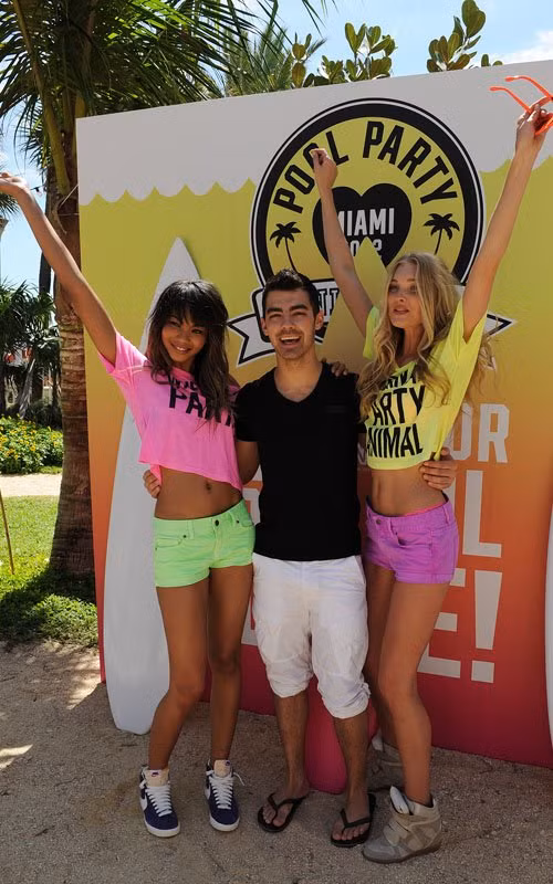 Joe Jonas quàng tay qua ôm eo hai siêu mẫu với nụ cười trên môi.