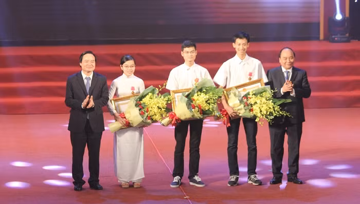 Thủ tướng Nguyễn Xuân Phúc và Bộ trưởng Bộ GD&amp;ĐT Phùng Xuân Nhạ trao tặng Huân chương Lao động hạng Ba cho học sinh đoạt giải Olympic quốc tế. (Ảnh: Thùy Linh)