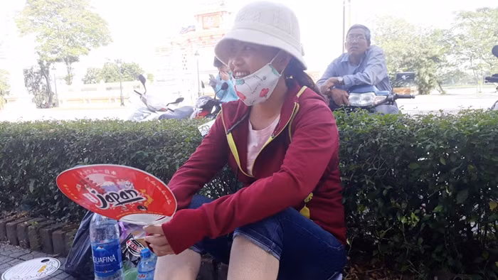 Thời tiết nắng nóng nên phụ huynh phải ngồi ở các bóng cây ven đường. Ảnh: TL