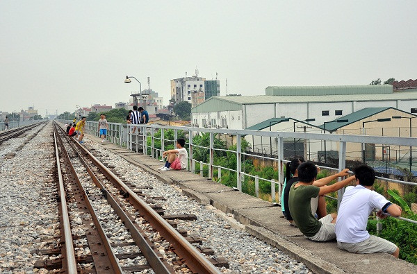 Các bạn trẻ ngồi vắt vẻo trên các hành lang cầu dẫn đường sắt để hóng gió, chuyện trò.