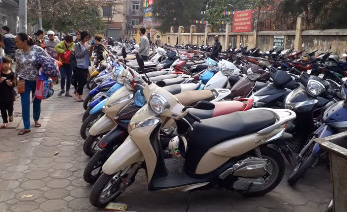 Mặc dù giấy phép tạm ghi rất rõ trong giờ cao điểm không được trông giữ xe nhưng quan sát của phóng viên có mặt 16h30 tại đây, bãi xe này vẫn có hàng trăm chiếc được dựng trên vỉa hè, gây cản trở cho người đi đường và phụ huynh đến đón con. Ảnh Trần Việt.
