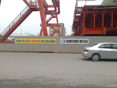 Những khẩu hiệu "Chúng tôi không làm phiền cho cộng đồng" được dán trên tường bao quanh khu vực công trường thi công đường vành đai 3. Những khẩu hiệu "Chúng tôi không làm phiền cho cộng đồng" được dán trên tường bao quanh khu vực công trường thi công đường vành đai 3.