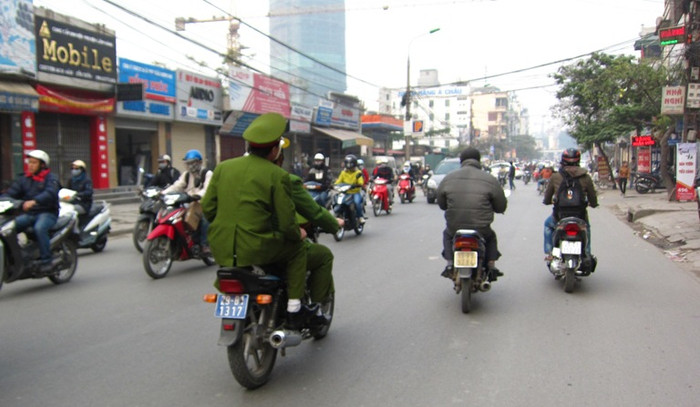 Trong khi những người xung quanh chấp hành nghiêm thì người mặc sắc phục cảnh sát ngồi sau xe biển xanh này lại "phớt lờ" mũ bảo hiểm.