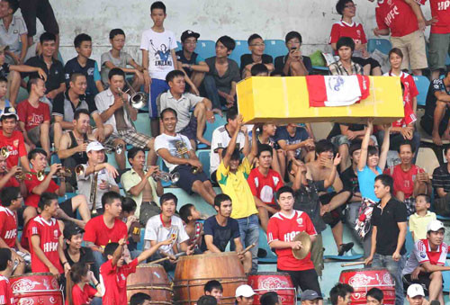 Còn NHM thì mang tới sân một chiếc quan tài được phủ lá cờ CLB Hải Phòng lên trên… Còn NHM thì mang tới sân một chiếc quan tài được phủ lá cờ CLB Hải Phòng lên trên…