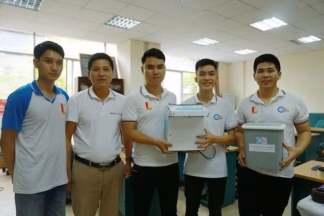 Hoàn cùng các bạn và giáo viên chụp hình bên hai phiên bản của chiếc máy rửa tay tự động (ảnh:NVCC)