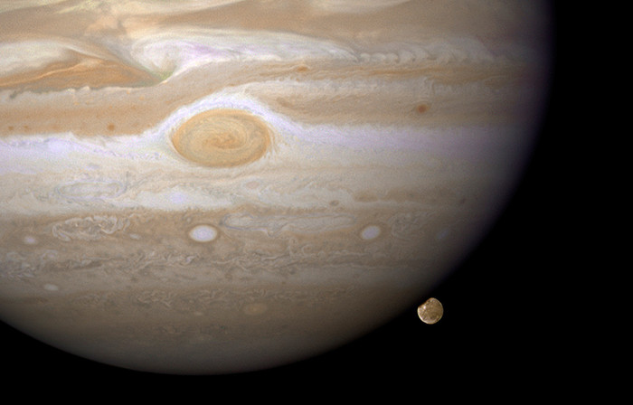 4. Vệ tinh của gã khổng lồ Jupiter Kính viễn vọng Hubble đã chộp được hình ảnh vệ tinh Ganymede của sao Mộc trước khi bị che khuất bởi chính hành tinh sao Mộc khổng lồ. Cứ 7 ngày, Ganymede lại hoàn thành 1 quỹ đạo quay xung quanh sao Mộc. Được tạo lên từ đá và băng, Ganymede là vệ tinh lớn nhất trong hệ mặt trời, nó thập chí còn lớn hơn cả sao Thủy. Tuy nhiên Ganymede lại trông như quả cầu tuyết bé nhỏ bên cạnh sao Mộc, hành tinh lớn nhất trong hệ mặt trời. Sao Mộc quá lớn nên ở đây chỉ thu được hình ảnh của nửa Nam bán cầu. Mặc dù sao Mộc cách xa 730 triệu km nhưng kính thiên văn Hubble vẫn thu được hình ảnh vô cùng sắc nét giúp các nhà thiên văn quan sát rõ ràng bề mặt vệ tinh Ganymede. Trên bề mặt hầu hết là những chòm màu trắng, các vệt sáng và tia sáng vật chất. Phía trên, bên trái là một nốt đỏ khổng lồ giống như mắt của sao Mộc. Ganymede ở phía sau sao Mộc, nó phản chiếu ánh sáng mặt trời và đi qua bầu khí quyển của sao Mộc.