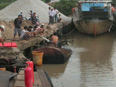 Tàu chở dầu bị cháy chìm dưới sông Mỹ Xuyên đang được trục vớt. Tàu chở dầu bị cháy chìm dưới sông Mỹ Xuyên đang được trục vớt.