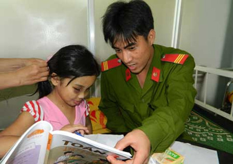 Cán bộ Công an huyện Nghĩa Hành hướng dẫn bài vở cho cháu Phi trong những ngày nằm viện