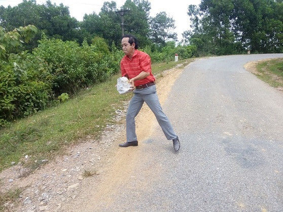 Thầy Lê Quốc Châu dọn viên đá chắn ngang đường để những người khác không gặp tai nạn. Bức ảnh được ghi lại trên đường thầy đi thiện nguyện về (Ảnh: Lê Phạm)