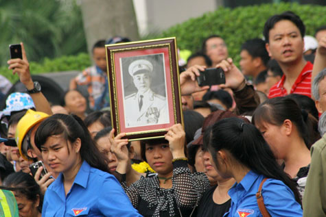 Một người phụ nữ kính cẩn đưa ảnh Đại tướng lên đầu..