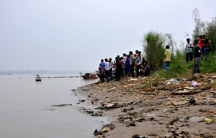 Nhiều người đã xuống sát dòng nước để đợi tin tìm kiếm của gia đình