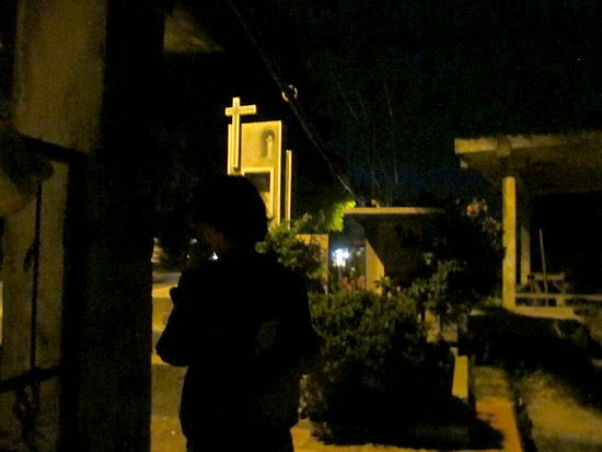 Một cô gái bán hoa nấp phía sau cổng nghĩa trang chờ khách