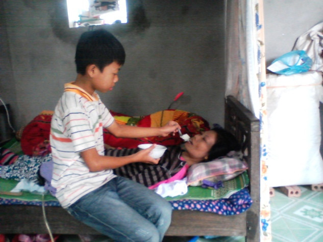 Cậu bé Đỗ Khắc Vinh đang bón cháo cho mẹ tại nhà. Cậu bé Đỗ Khắc Vinh đang bón cháo cho mẹ tại nhà.