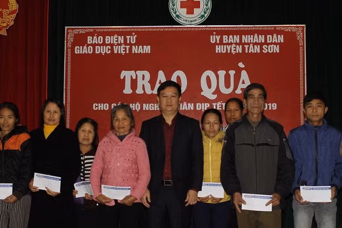 Ông Nguyễn Tiến Bình chụp ảnh lưu niệm với bà con nghèo ở xã Tam Thanh, xã Vinh Tiền huyện Tân Sơn (ảnh Trinh Phúc).