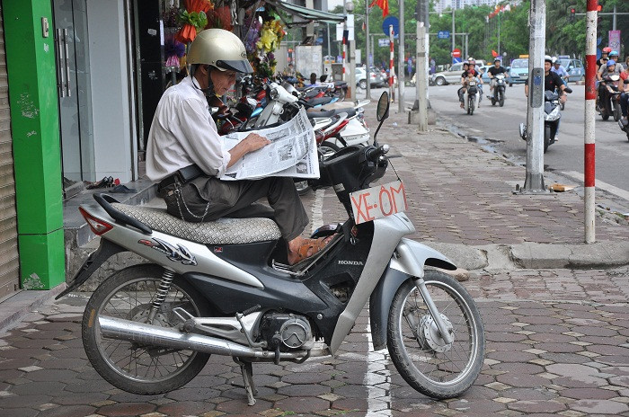 Bác Trung đang tranh thủ đọc báo khi không có khách Bác Trung đang tranh thủ đọc báo khi không có khách